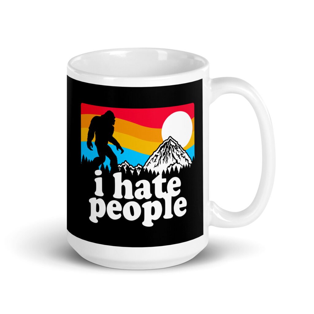 White coffee mug with graphic of Bigfoot walking into the sunset with the text 'I hate people' printed on both sides.