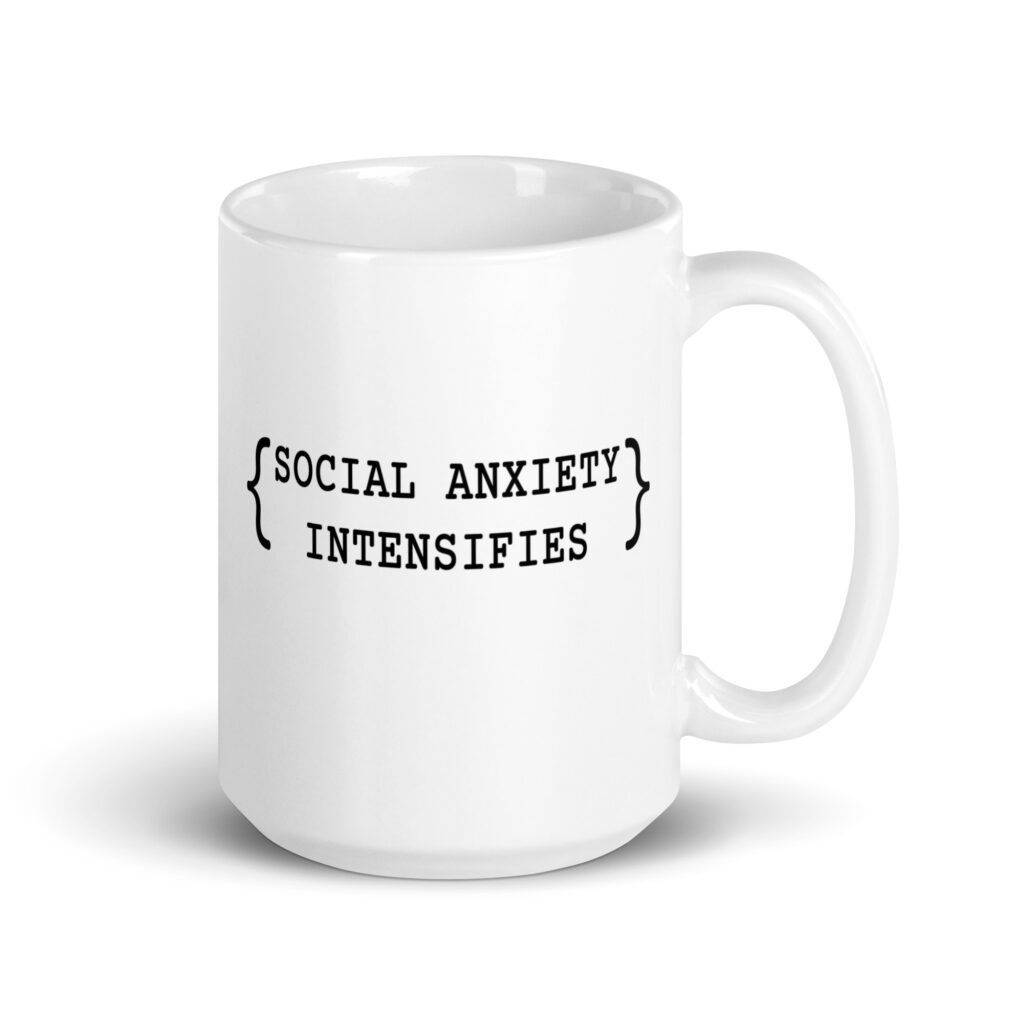 White ceramic coffee mug with the text 'Social anxiety intensifies' printed on both sides.