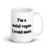 White ceramic mug with the pun phrase 'I'm a social vegan. I avoid meet.' printed on both sides.