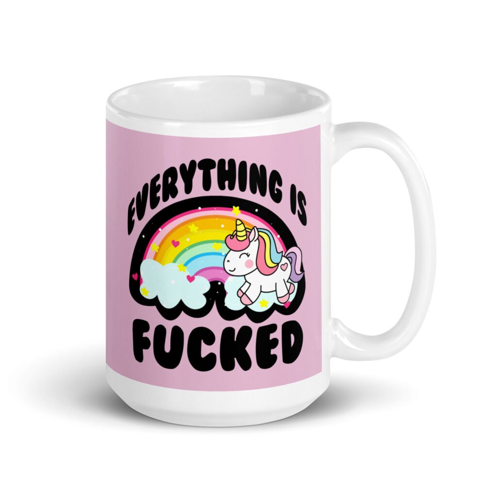 Pink and white ceramic coffee mug with a graphic of a kawaii style unicorn and a pastel rainbow with the text 'Everything is fucked' printed on both sides. The background is pink.