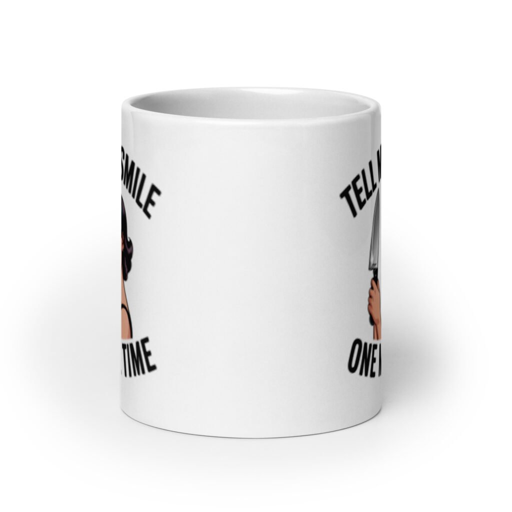 White ceramic mug with graphic of a woman holding a knife and the phrase 'Tell me to smile one more time' printed on both sides.