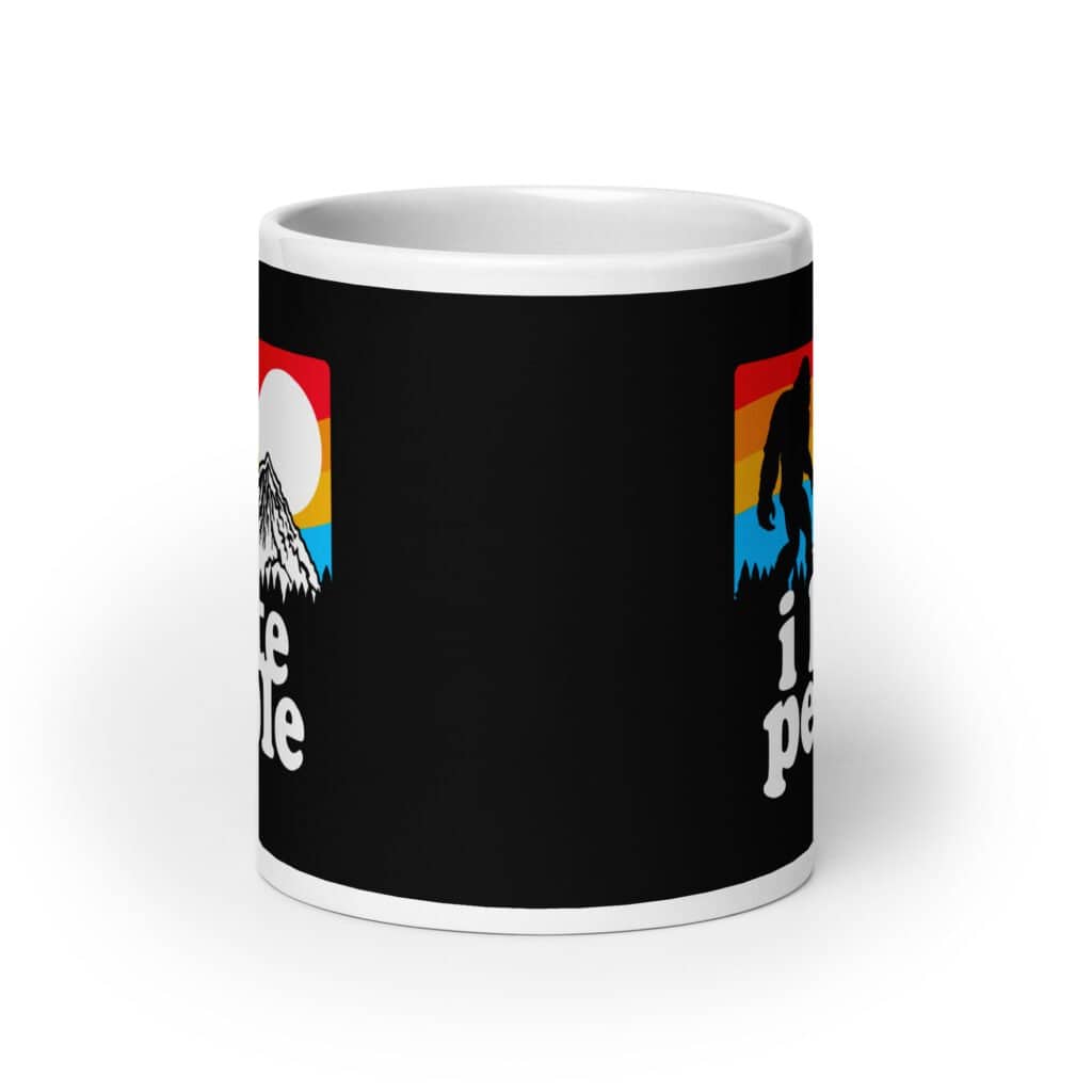 White coffee mug with graphic of Bigfoot walking into the sunset with the text 'I hate people' printed on both sides.