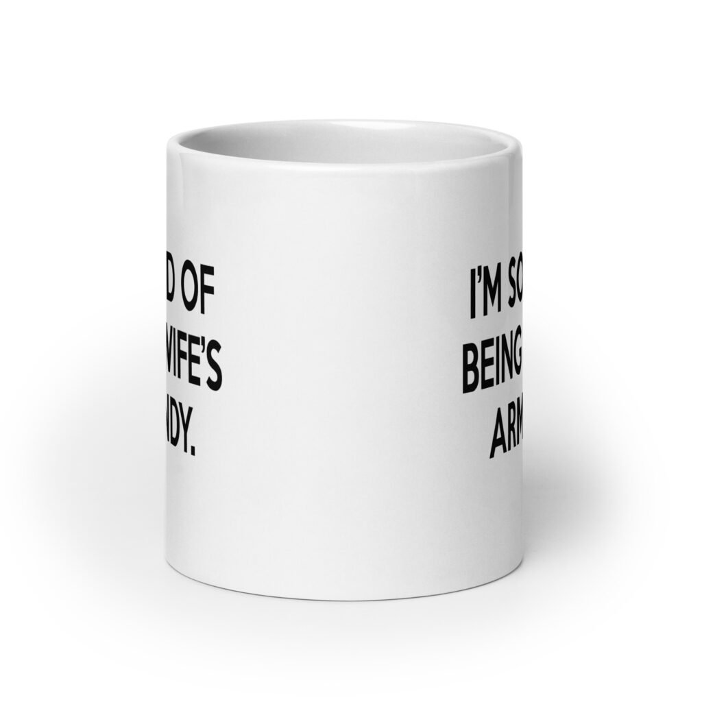 White ceramic coffee mug with the funny phrase 'I'm so tired of being my wife's arm candy' printed on both sides.