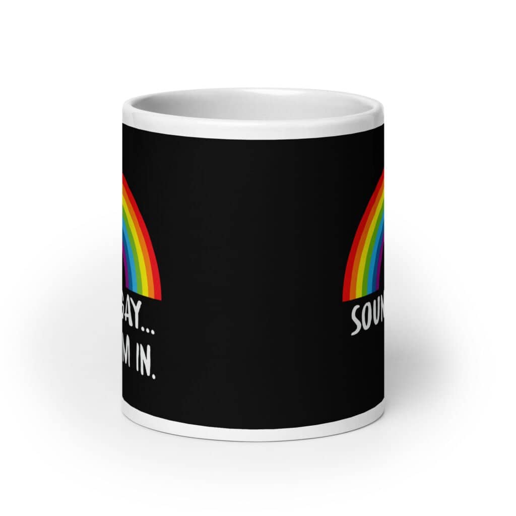 Black and white ceramic coffee mug that has an image of a rainbow and the text 'Sounds gay... I'm in.' printed on both sides.