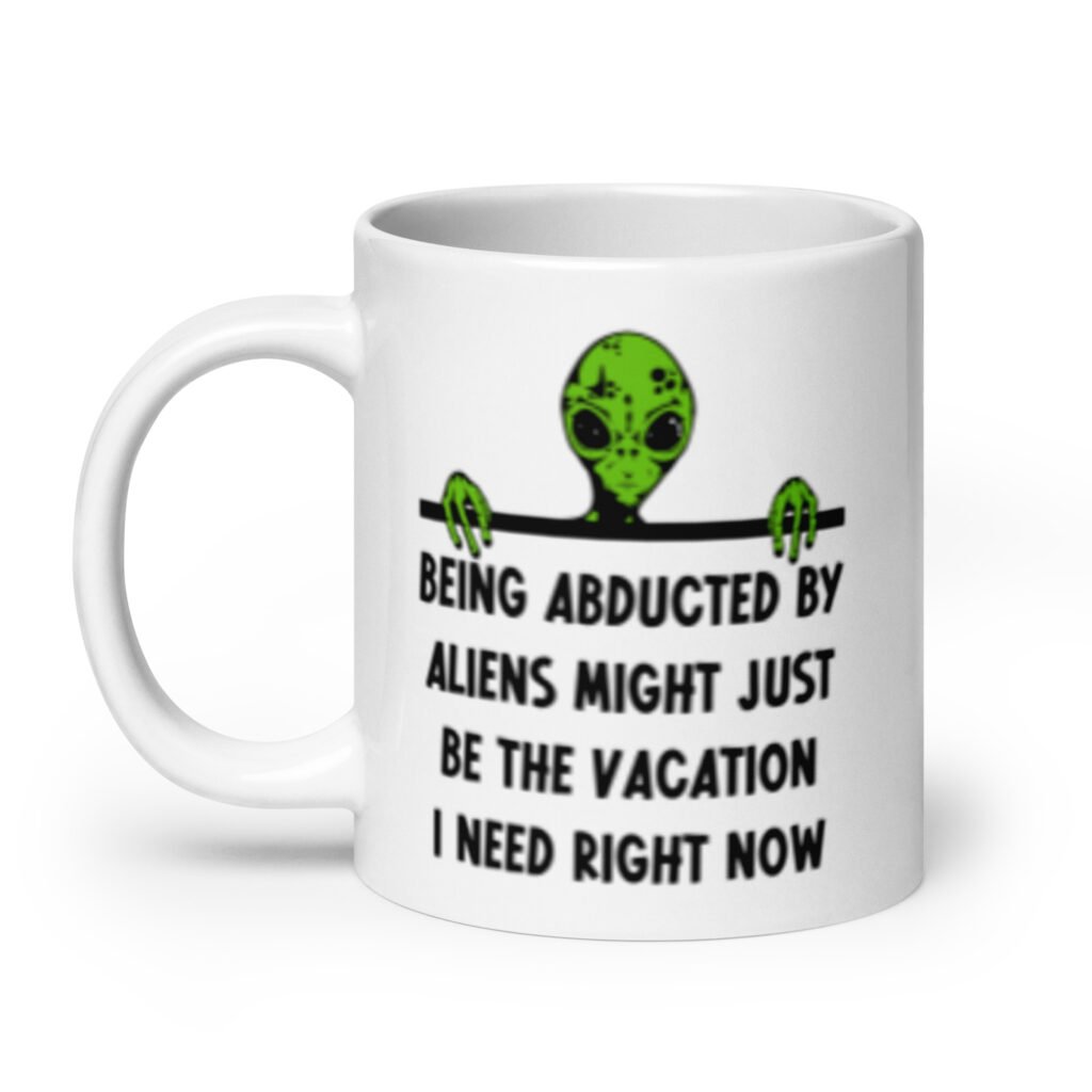 White ceramic mug with image of an alien and the words 'Being abducted by aliens might just be the vacation I need right now' printed on both sides.