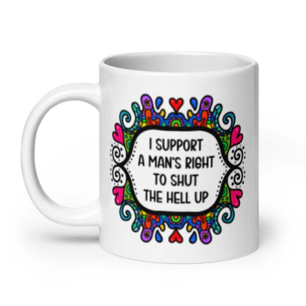 White ceramic mug with a colorful doodle graphic and the words 'I support a man's right to shut the hell up.' The design is printed on both sides of the mug.