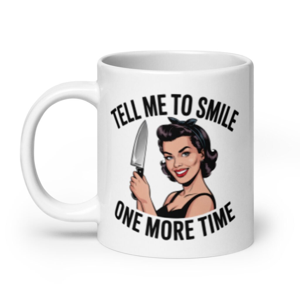 White ceramic mug with graphic of a woman holding a knife and the phrase 'Tell me to smile one more time' printed on both sides.