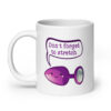 White ceramic coffee mug that has image of a purple anal plug with a smile face. There is a speech bubble above with the words 'Don't forget to stretch'. The graphics are printed on both sides of the mug.