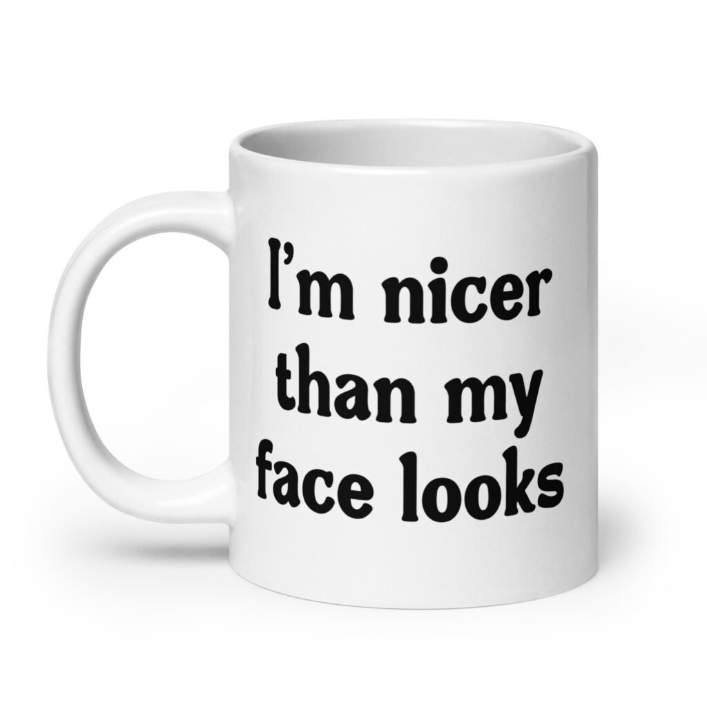 White ceramic coffee mug with the text 'I'm nicer than my face looks' printed on both sides.