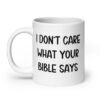 White ceramic coffee mug with the text 'I don't care what your bible says' printed on both sides.