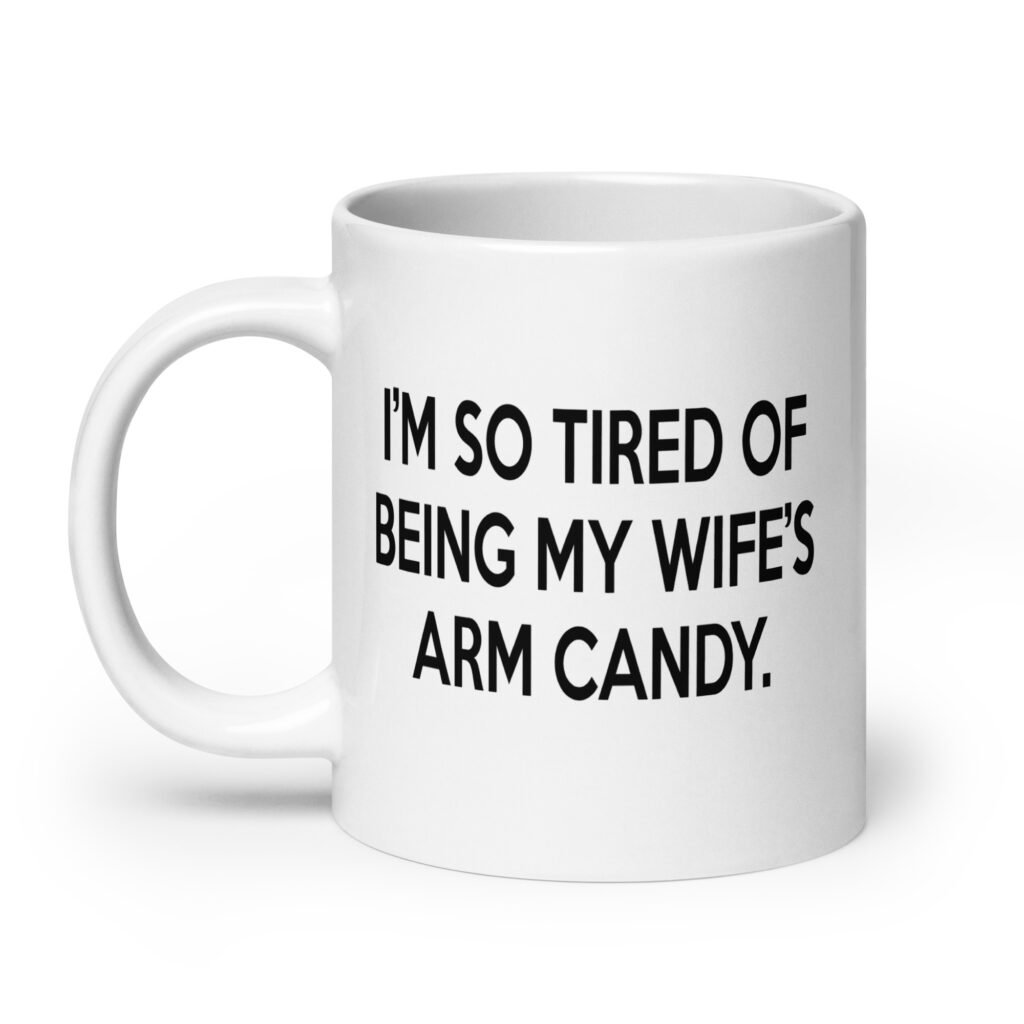 White ceramic coffee mug with the funny phrase 'I'm so tired of being my wife's arm candy' printed on both sides.