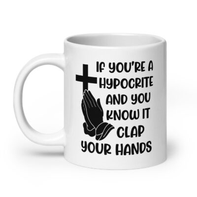 White ceramic mug with image of a cross and praying hands & the text 'If you're a hypocrite and you know it clap your hands' printed on both sides.