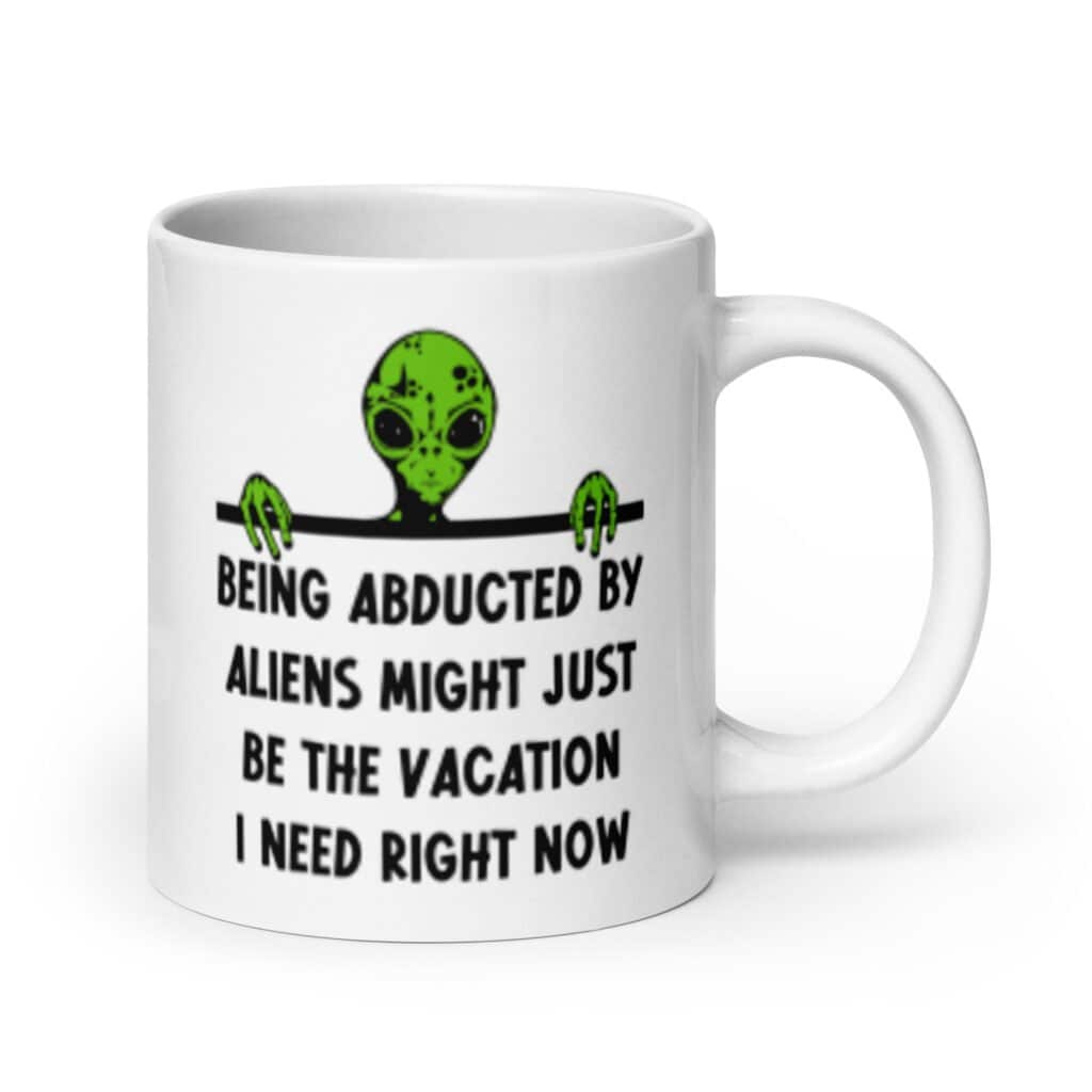 White ceramic mug with image of an alien and the words 'Being abducted by aliens might just be the vacation I need right now' printed on both sides.