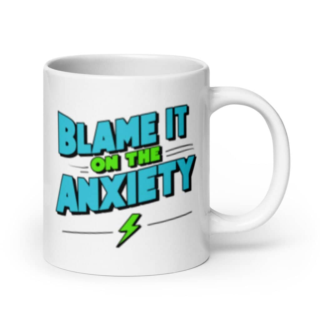 White ceramic mug with the phrase 'Blame is on the anxiety' printed on both sides of the mug. The graphics are bold and in aqua and lime green.