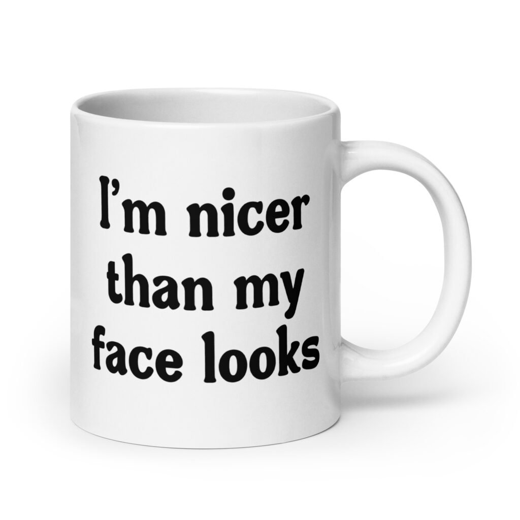 White ceramic coffee mug with the text 'I'm nicer than my face looks' printed on both sides.