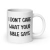 White ceramic coffee mug with the text 'I don't care what your bible says' printed on both sides.