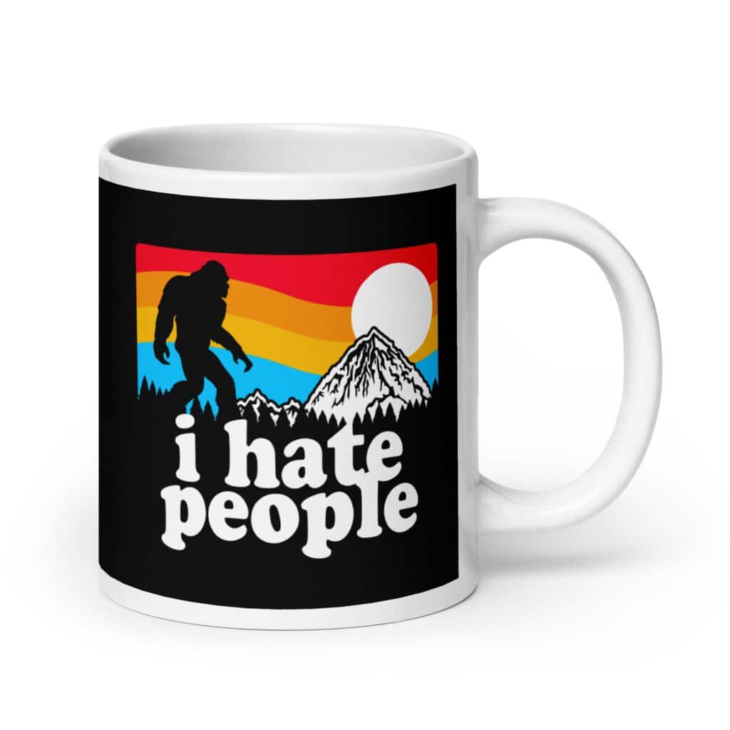 White coffee mug with graphic of Bigfoot walking into the sunset with the text 'I hate people' printed on both sides.