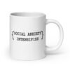 White ceramic coffee mug with the text 'Social anxiety intensifies' printed on both sides.