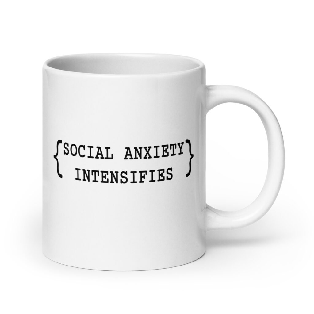 White ceramic coffee mug with the text 'Social anxiety intensifies' printed on both sides.