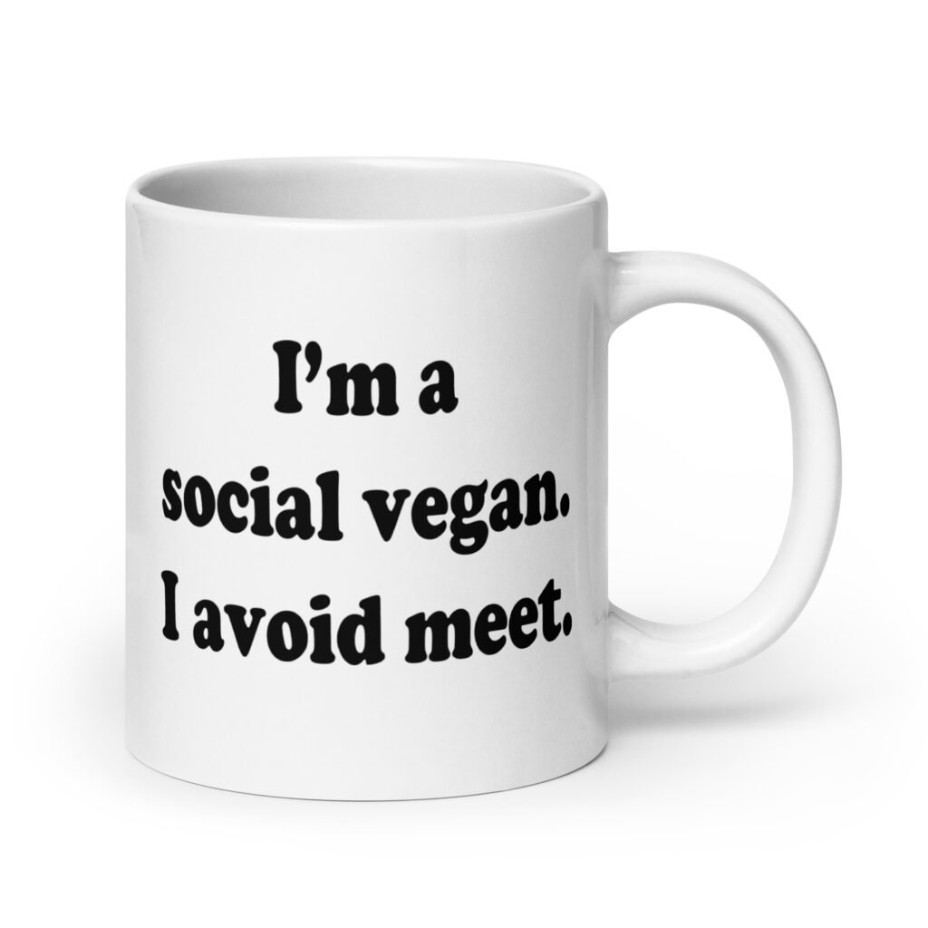 White ceramic mug with the pun phrase 'I'm a social vegan. I avoid meet.' printed on both sides.