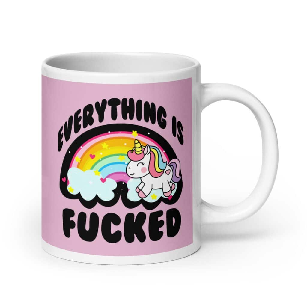 Pink and white ceramic coffee mug with a graphic of a kawaii style unicorn and a pastel rainbow with the text 'Everything is fucked' printed on both sides. The background is pink.