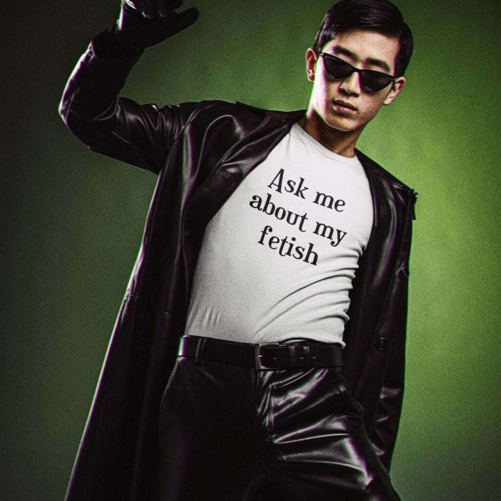 Man wearing black leather jacket and white t-shirt with the text 'Ask me about my fetish' printed on the front.