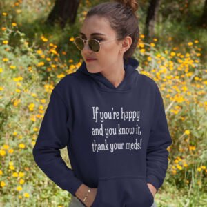 Woman standing near flowers wearing a navy blue hoodie sweatshirt with the text 'If you're happy and you know it, thank your meds!' printed on the front.