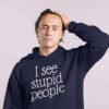 Exasperated looking man wearing a navy blue hoodie sweatshirt with the text 'I see stupid people' printed on the front.