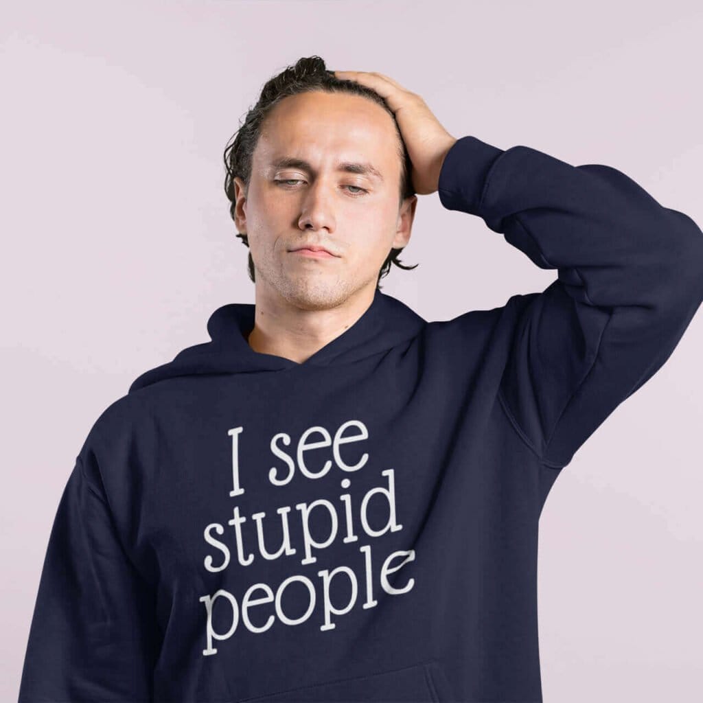 Exasperated looking man wearing a navy blue hoodie sweatshirt with the text 'I see stupid people' printed on the front.