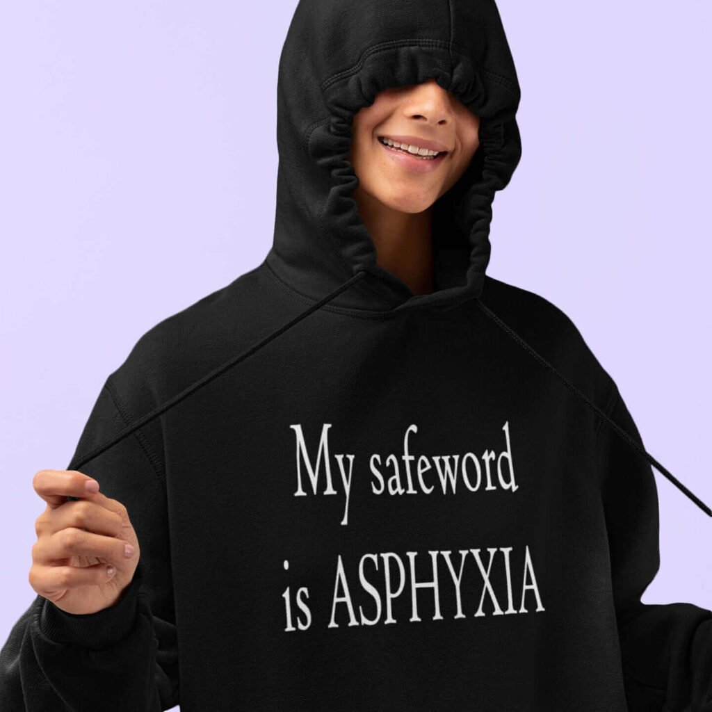Woman wearing a black hoodie sweatshirt with the drawstrings pulled around her face. The text 'My safeword is asphyxia' is printed on the front of the hoodie.