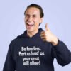 Smiling funny man giving the thumbs up sign. He is wearing a navy blue hoodie sweatshirt with the phrase Be fearless. Fart as loud as your anus will allow printed on the front.