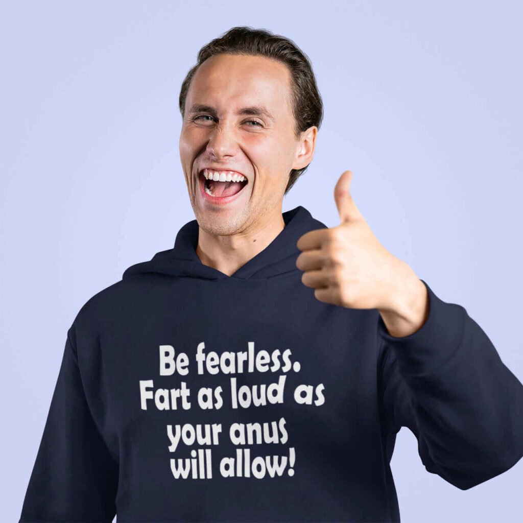 Smiling funny man giving the thumbs up sign. He is wearing a navy blue hoodie sweatshirt with the phrase Be fearless. Fart as loud as your anus will allow printed on the front.