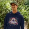 Man wearing a navy blue hoodie sweatshirt with a colorful boho rainbow floral design and the text 'Bad Vibes Only' printed on the front.