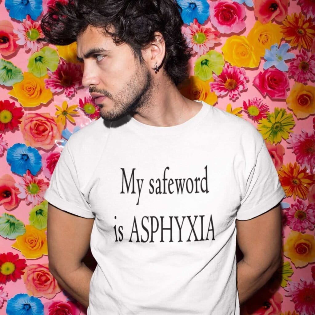 Man wearing a white t-shirt with the text 'My safeword is asphyxia' printed on the front.