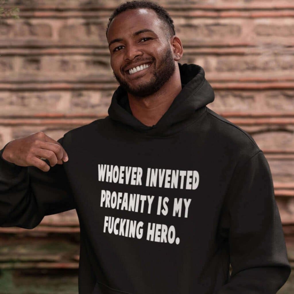 Smiling man wearing a black hoodie sweatshirt with the text 'Whoever invented profanity is my fucking hero.' printed on the front.