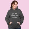 Woman wearing dark grey hoodie sweatshirt with the text 'Ask me about my fetish' printed on the front.