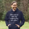 Smiling man wearing a navy blue biblical satire hoodie sweatshirt with the text 'Thou shalt not inflict thy religious crap upon others.' printed on the front.