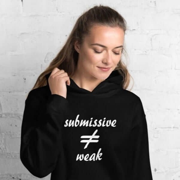 Woman wearing a black hoodie sweatshirt with the text 'submissive does not equal weak' printed on the front.