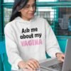 Woman wearing a white hoodie sweatshirt with the text 'Ask me about my VAGINA' printed on the front.