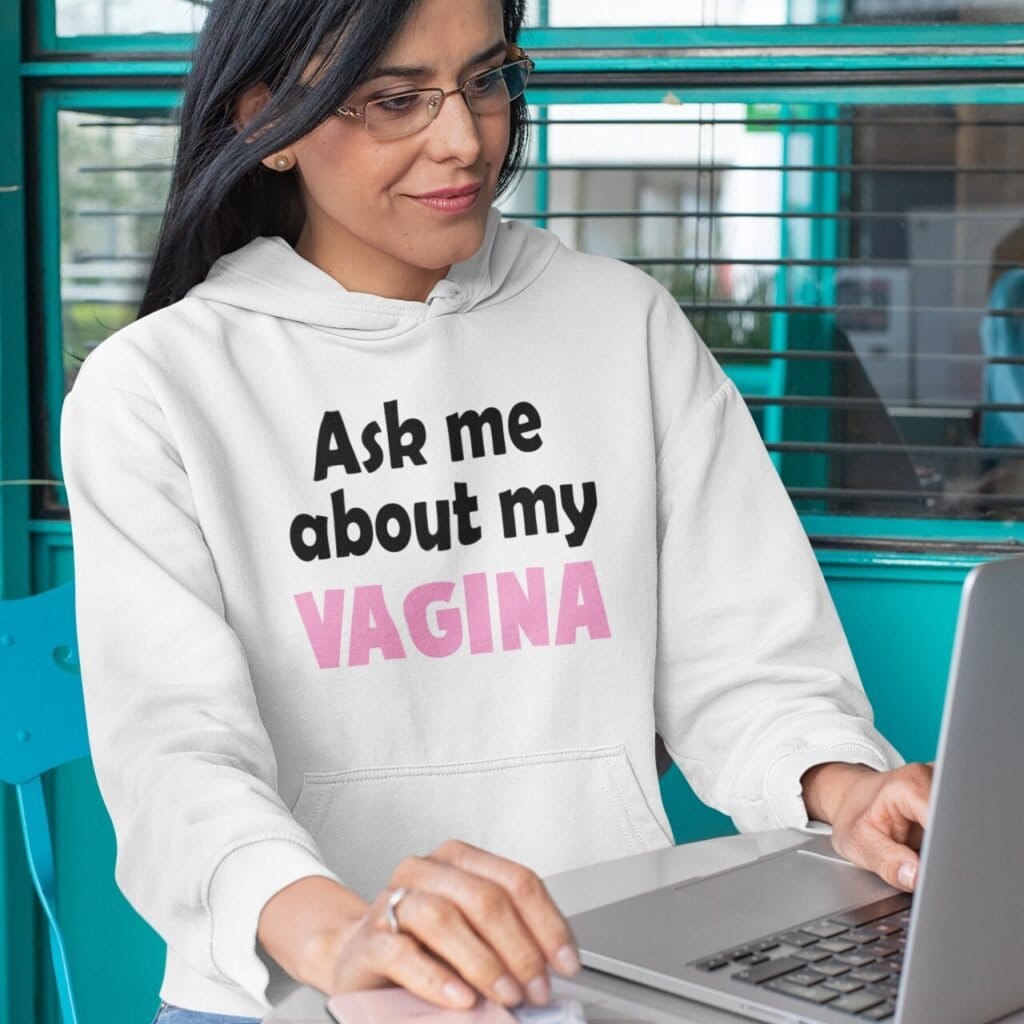 Woman wearing a white hoodie sweatshirt with the text 'Ask me about my VAGINA' printed on the front.