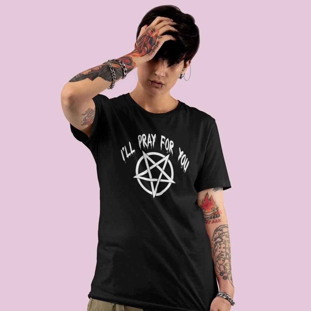 Edgy looking woman wearing a black t-shirt with image of a pentagram and the text 'I'll pray for you' printed on the front.
