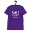 Purple t-shirt with the text 'Smile if you take it in the ass' printed on the front. The word 'smile' is large and the words 'take it in the ass' are much smaller.