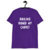 Purple t-shirt with the text 'Bukkake ruined my carpet' in drippy font printed on the front.