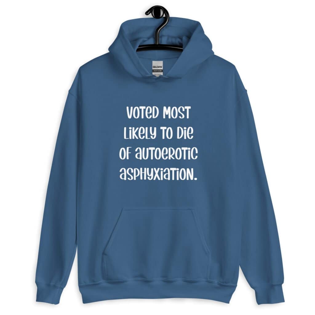 Indigo blue hoodie sweatshirt with the hood up covering some of her face. The hoodie has the text 'Voted most likely to die of autoerotic asphyxiation.' printed on the front.