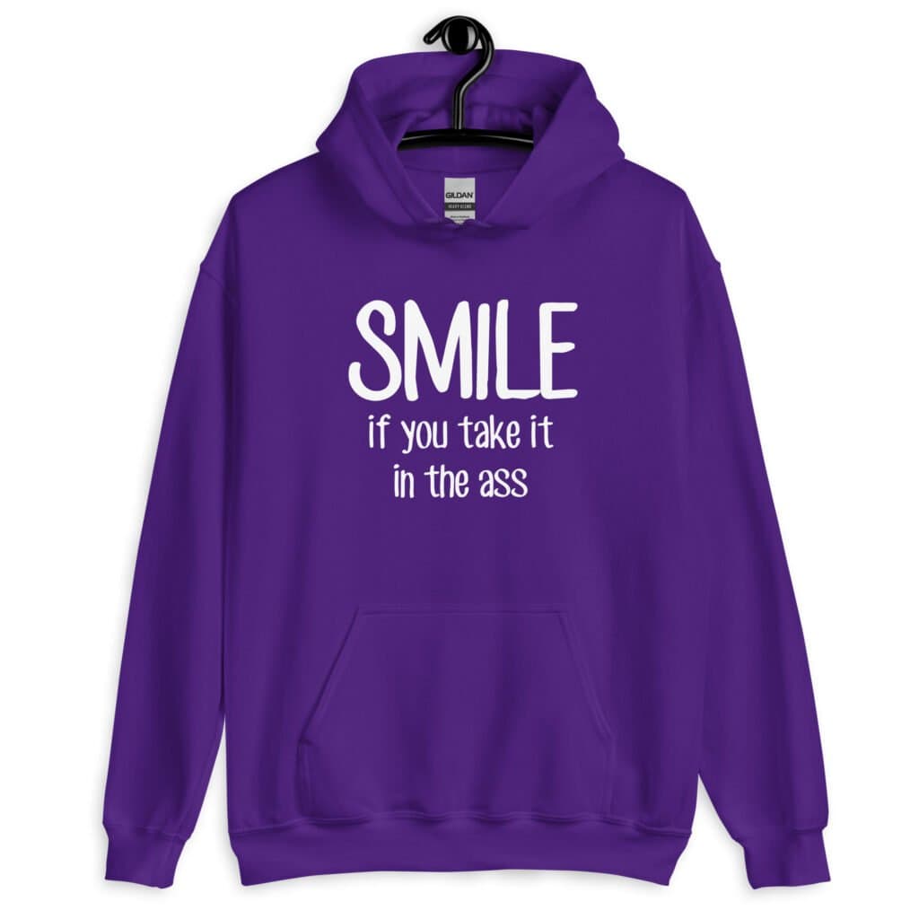 Purple hoodie sweatshirt with the text 'Smile if you take it in the ass' printed on the front. The word 'smile' is large and the words 'take it in the ass' are much smaller.