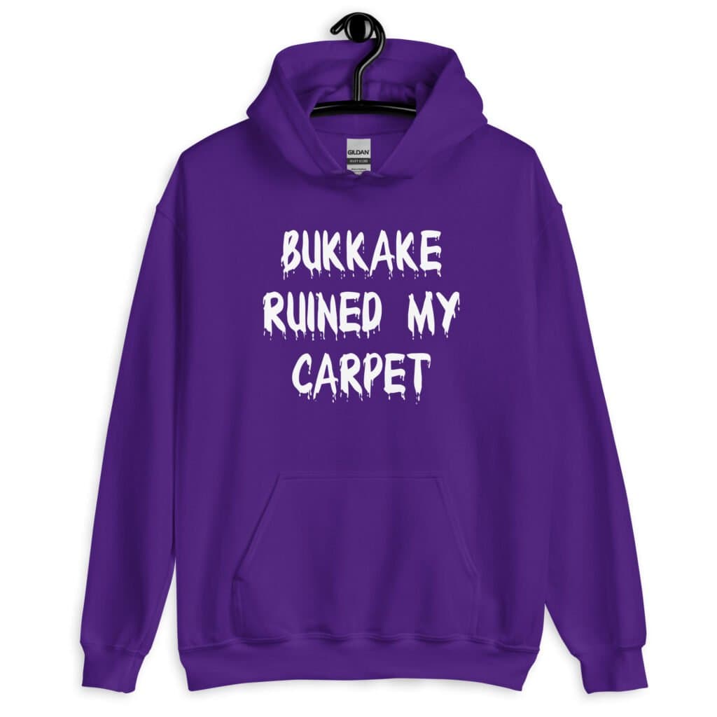 Purple hoodie sweatshirt with the text 'Bukkake ruined my carpet' in drippy font printed on the front.
