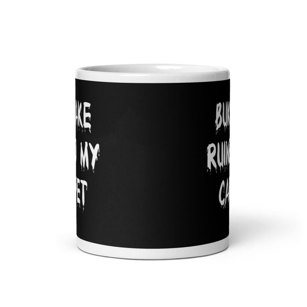White and black ceramic coffee mug with the text 'Bukkake ruined my carpet' printed in drippy font on both sides.