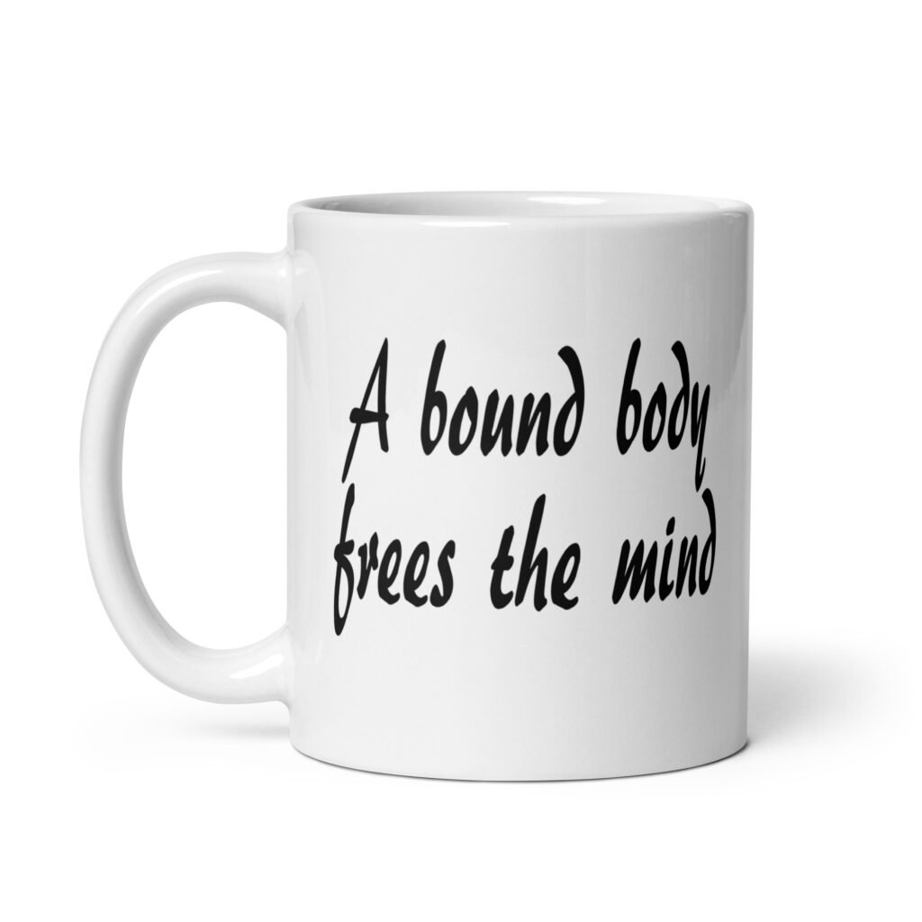White ceramic coffee mug with the text 'A bound body frees the mind' printed on both sides.