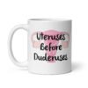 White ceramic mug with image of a uterus and the text 'Uteruses before duderuses' printed on both sides.