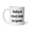 White ceramic coffee mug with the text 'Reading can seriously damage your ignorance.' printed on both sides.